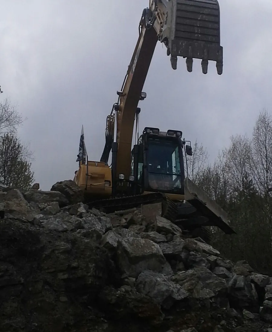 Gravemaskin på steinhaug