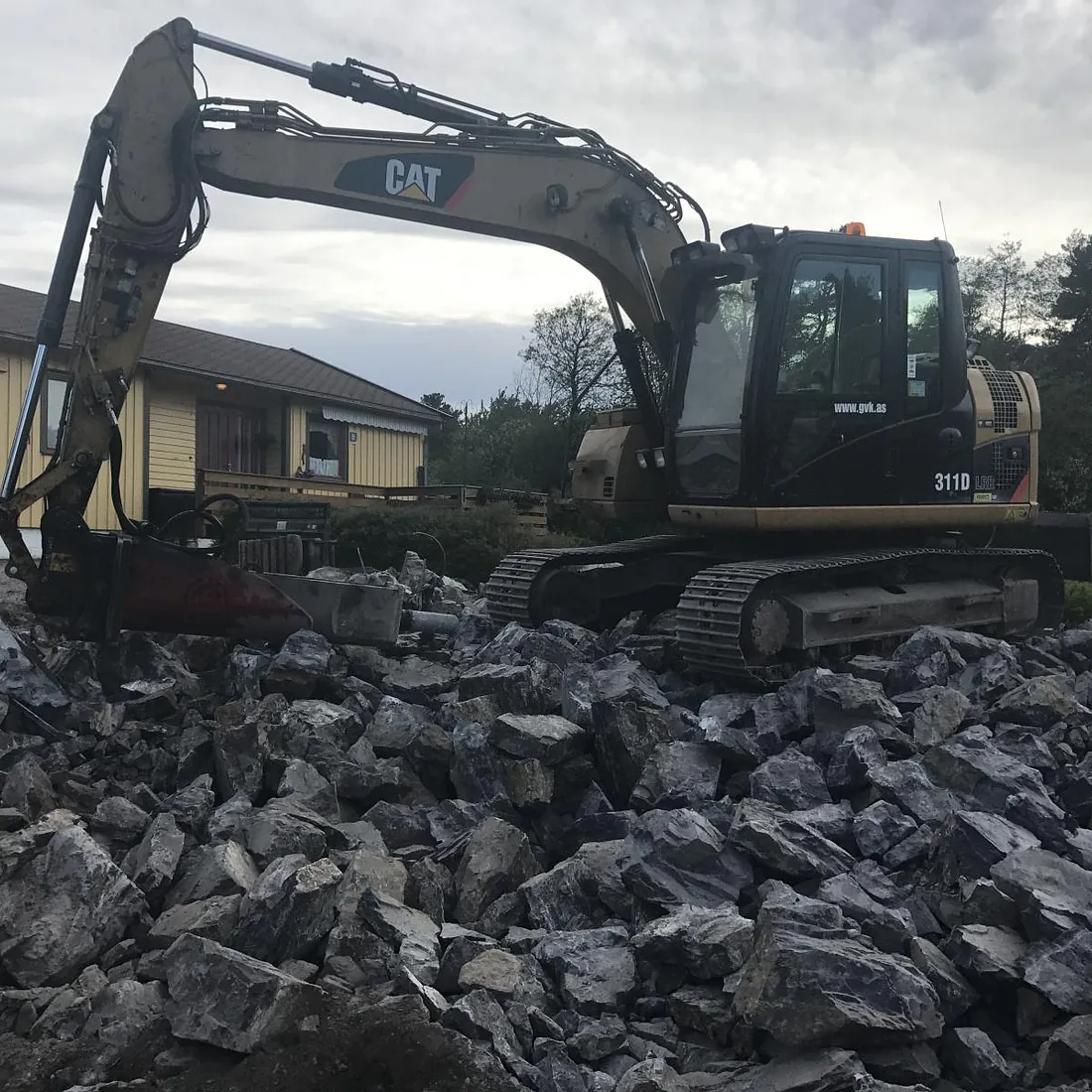 Gravemaskin graver i steinhaug